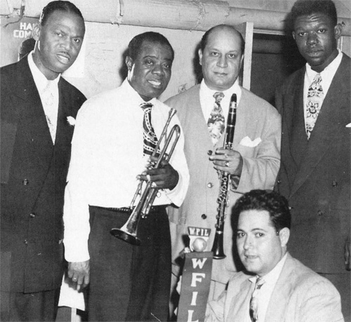 Al Rose, at the microphone, poses with (from left) Earl Hines, Louis Armstong, Barney Bigard and Arvel Shaw at Philadelphia's Academy of Music in 1947.