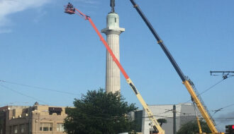 Work crews use cranes as they prepare to remove a statue of Confederate General Robert E. Lee from a pedestal in New Orleans